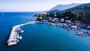 An aerial view of a coastal town with a marina, houses, and hills in the background.