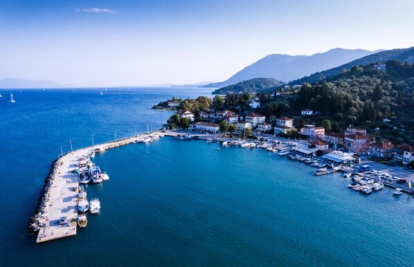 An aerial view of a coastal town with a marina, houses, and hills in the background.