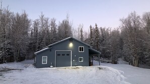 Une maison de plain-pied à l’extérieur de couleur gris foncé, avec un garage et une allée menant à l’entrée.