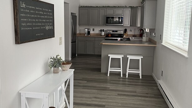 Une cuisine moderne avec des meubles gris, un îlot central et une console blanche.