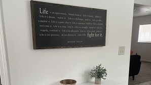 Une console blanche, ornée d’un bol et d’un vase, et une citation inspirante affichée sur le mur au-dessus.