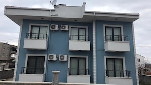 A multi-story building with balconies, air conditioning units, and a satellite dish. - Liya Pansiyon (Ezine)