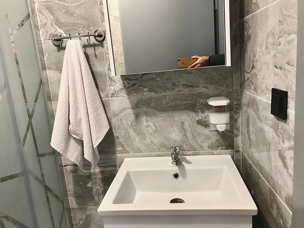 Un baño con un lavabo blanco, un perchero y un espejo.
