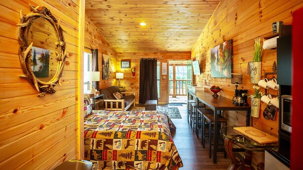 L’intérieur d’une cabane en rondins comprend un lit, un coin repas et une cuisine.