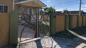 A residential building with a gated entrance, a small porch, and a clear sky. - Williams Oasis (Falmouth)