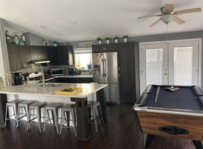 Enjoy meals and games in this kitchen and living area featuring a central island with bar stools, an oven, and a pool table.