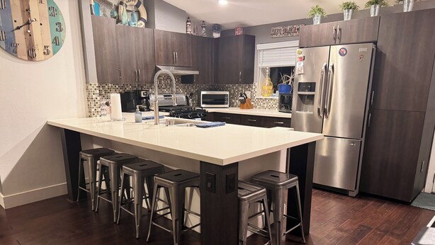 Una cocina moderna con una isla central, electrodomésticos de acero inoxidable y gabinetes de madera oscura.