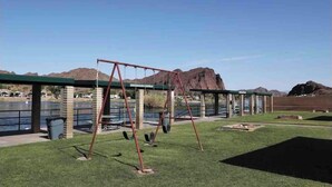 Un parque con columpios, una zona techada y vistas a montañas.