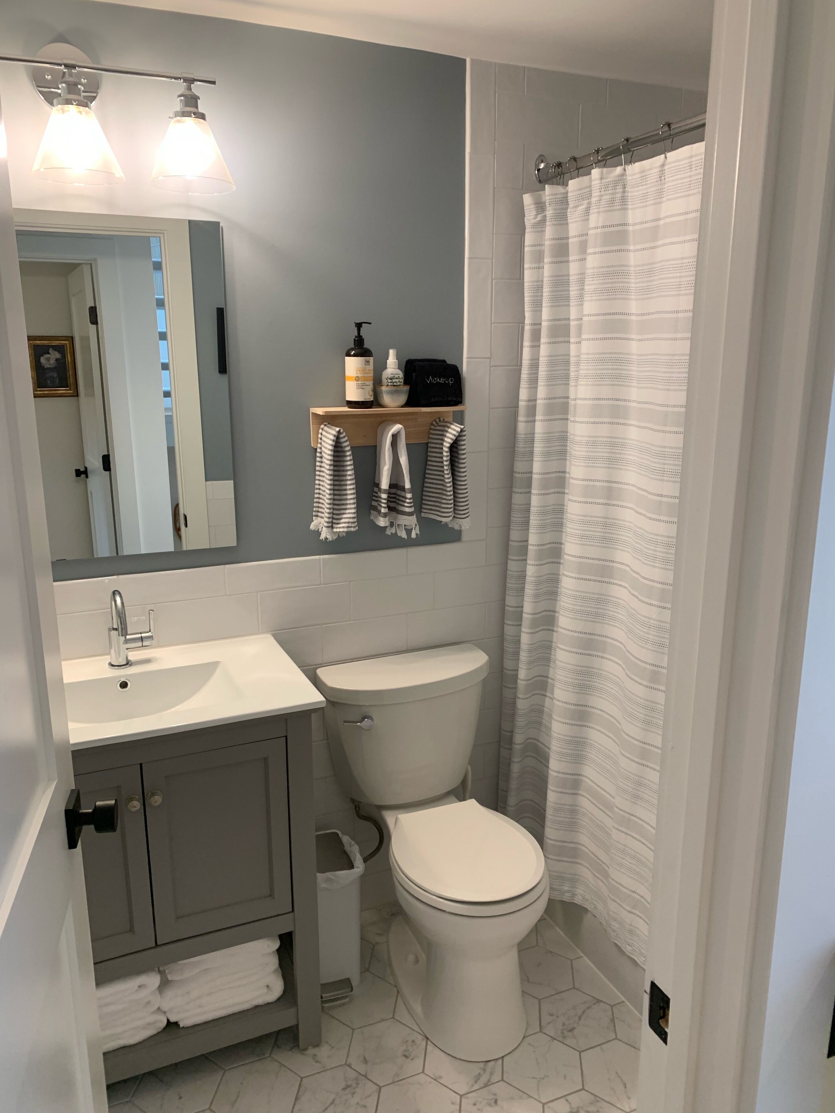 Ein Badezimmer mit Waschbecken, Toilette, Duschvorhang und Spiegel.