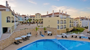 Um resort com piscina, espreguiçadeiras e um pátio com palmeiras.