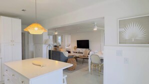 A modern kitchen with white cabinetry, a central island, and a hanging light fixture.