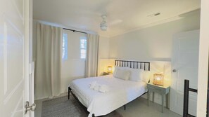 A bedroom with a bed, two bedside tables with lamps, a ceiling fan, and a window with curtains. - Murrells inlets #A Great duplex walk to the beach (Murrells Inlet)