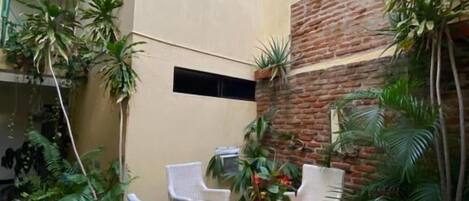 Un área de estar al aire libre con mobiliario de mimbre y plantas en macetas.