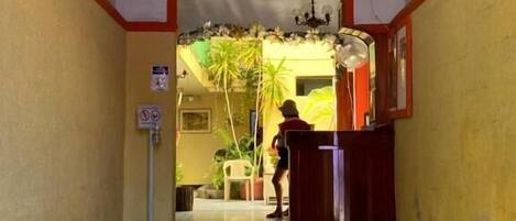 A hallway with a reception desk, a no-smoking sign, and a decorative ceiling.