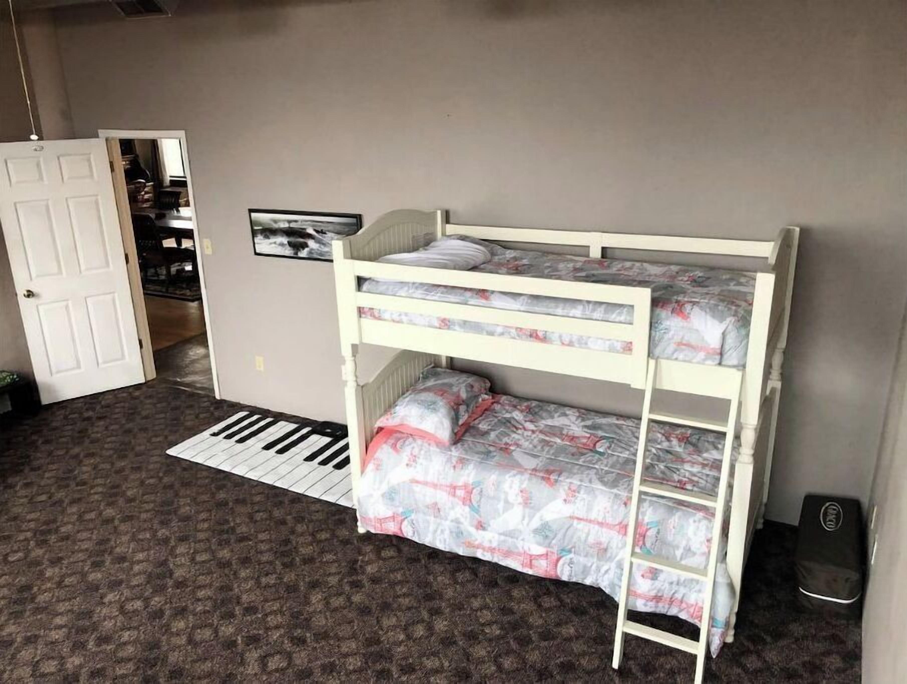 A bunk bed room with a door, a framed picture, and a small rug.