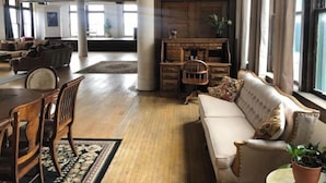 Un salon spacieux avec une grande fenêtre, un canapé, une table basse en bois et une cheminée.
