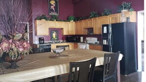 Une cuisine avec des meubles de rangement en bois, un réfrigérateur noir et une table à manger avec des chaises.