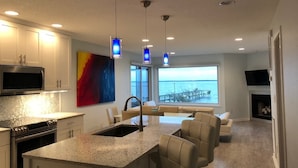 A modern kitchen with a large island, stainless steel appliances, and pendant lighting. - Waterfront Gorgeous Beach Home-Sunsets & Spa Bath (Duck)