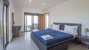 Ein modernes Hotelzimmer mit einem großen Bett, einem Schreibtisch und durch eine Schiebetür erreichbarer Sitzbereich im Freien.