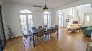 Ein geräumiger Raum mit Holzboden, einem Esstisch mit Stühlen, einer Couch und einem Kamin.