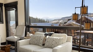 A cozy living room with a sofa and armchair, a large window with a mountain view, and a hanging light fixture. - Private Hot Tub/Brand New Luxury Townhome/Short Drive to Slopes! (Keystone)
