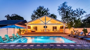 Una casa con piscina, mobiliario exterior y un patio cubierto.