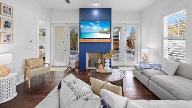 Una sala de estar con televisor de pantalla plana montado en una pared azul, un sofá, un sillón y una chimenea.
