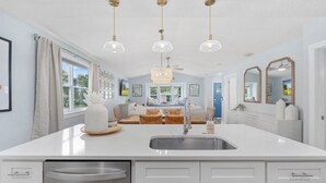 Una cocina moderna con una isla central, electrodomésticos de acero inoxidable e iluminación colgante.