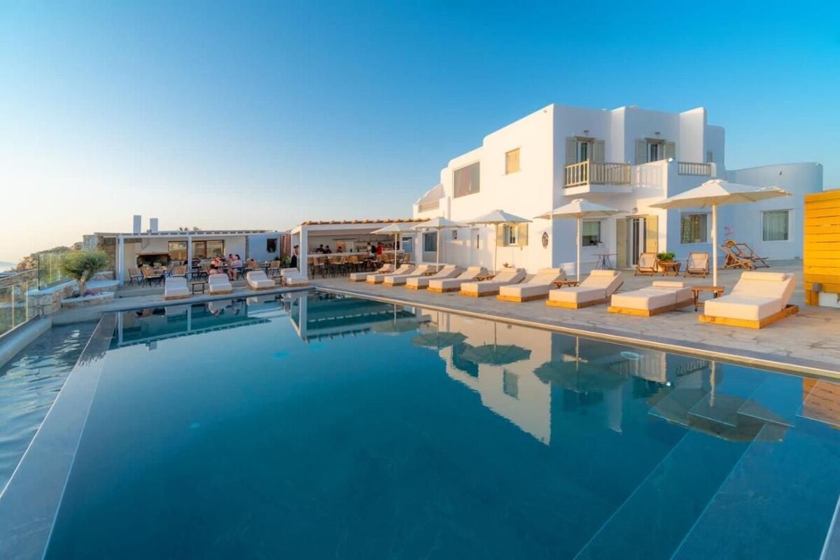 Un hotel moderno con piscina, sillas de descanso y comedor.