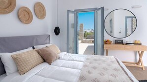Un dormitorio con cama, escritorio, espejo y vistas al exterior.