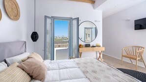 Un dormitorio con cama, escritorio de madera, silla, espejo y televisor en la pared.