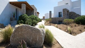 Un edificio moderno con muros de piedra y blanco, una escalera de piedra y un sendero pavimentado.
