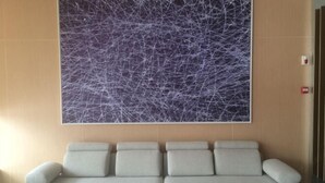 A modern waiting area with a sofa and a large abstract painting on the wall. - Jinjiang Inn (Xianju Huancheng North Road) (Xianju)
