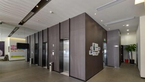 A modern hotel lobby with a reception desk, elevators, and a large potted plant. - Jinjiang Inn (Xianju Huancheng North Road) (Xianju)