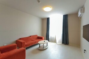 A modern living room with a sofa, a small round table, and a ceiling light. - Jinjiang Inn (Xianju Huancheng North Road) (Xianju)