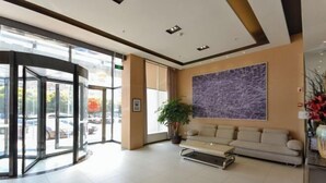 A lobby with a glass entrance, a sofa, a potted plant, and a large abstract painting on the wall. - Jinjiang Inn (Xianju Huancheng North Road) (Xianju)