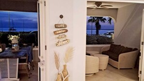 An open-plan living area with a view of the sea, a cozy seating area, and a wall-mounted sign with a life quote. - Oceanfront large 4-p luxury groundfloor apartment  (Kralendijk)