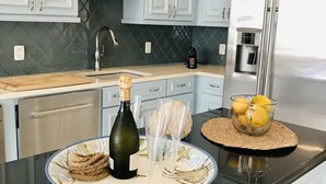 A kitchen with white cabinets, a black countertop, a stainless steel refrigerator, and a coffee maker. - Oceanfront large 4-p luxury groundfloor apartment  (Kralendijk)