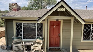 A small building with a red door, a number 300 sign above it, and a patio with a table and chairs.