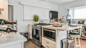 A modern kitchen with stainless steel appliances, a white countertop, and a large island with seating.