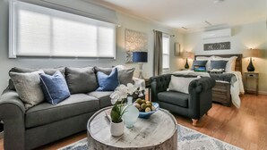 A modern living room with a grey sofa, a black armchair, and a coffee table with decorative items.