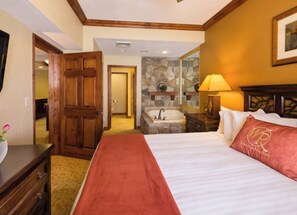Relax in a traditional room with a large bed, bathtub, and wooden headboard.