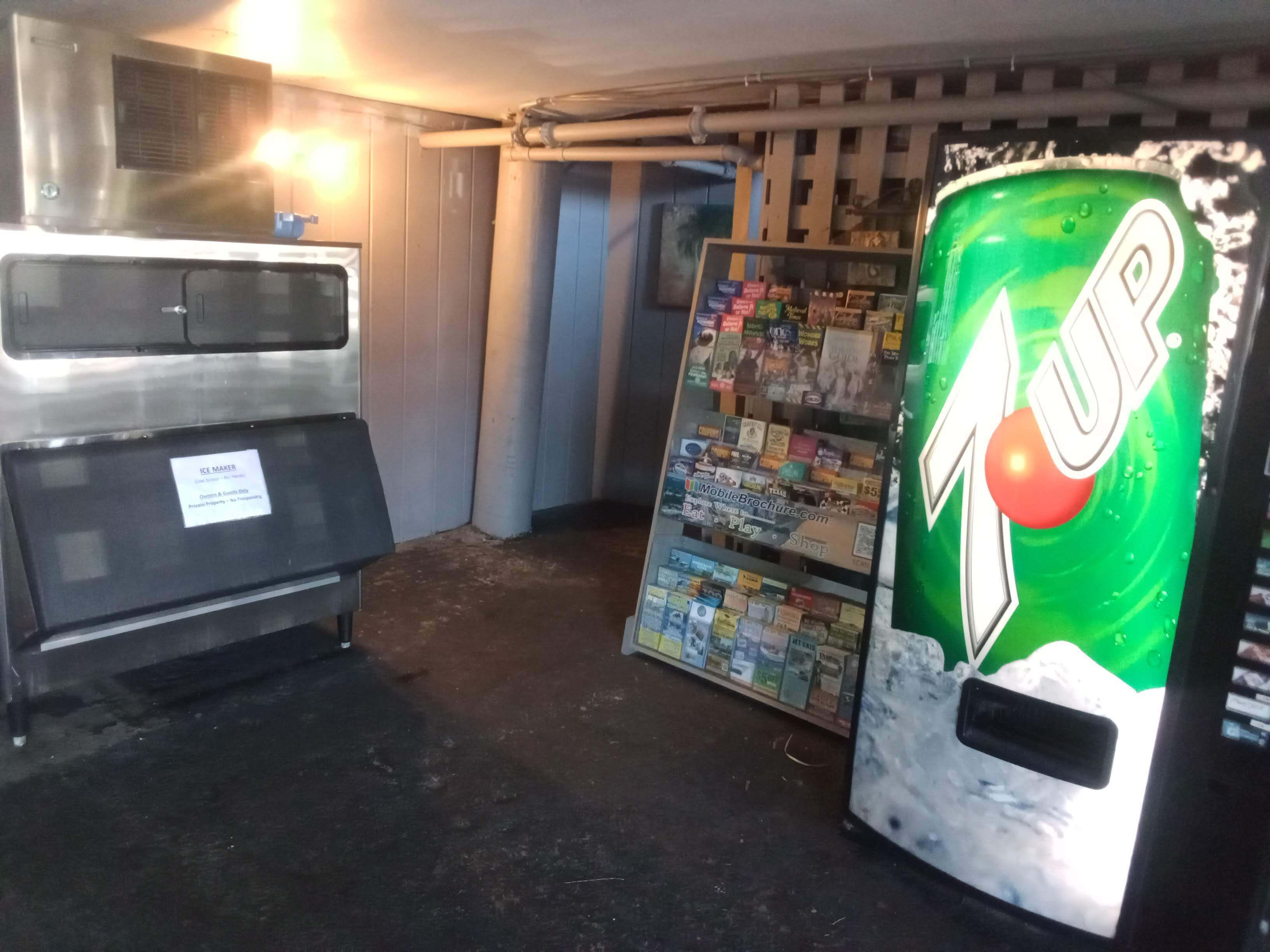 A vending machine with a 7UP logo, a freezer, and a display of mobile brochures.