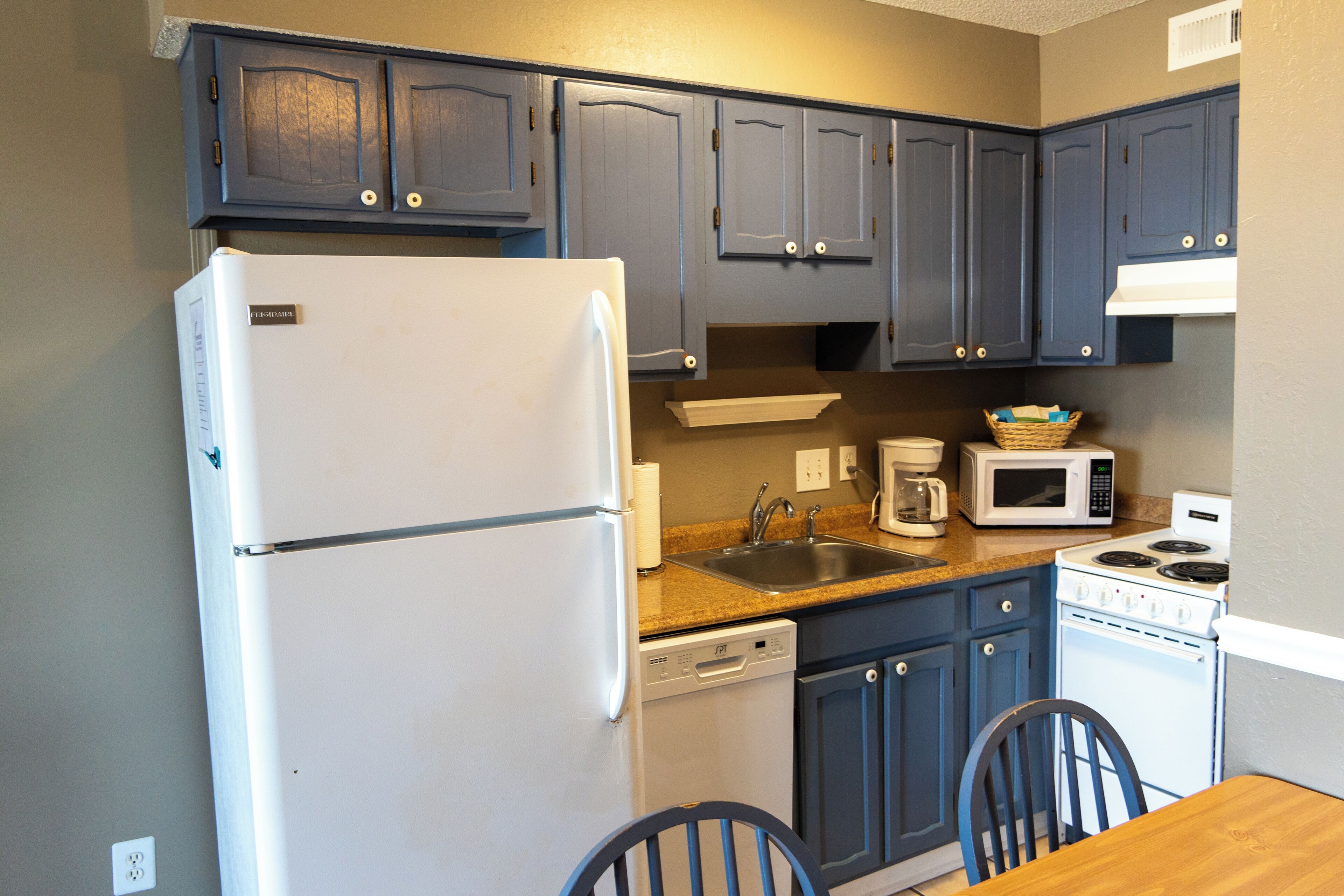 A compact kitchen with a refrigerator, microwave, stove, sink, and dishwasher.
