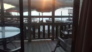 A wooden deck with a glass table and chairs, overlooking a body of water and a sunset. - Seawatch Inn at the Landing (Murrells Inlet)