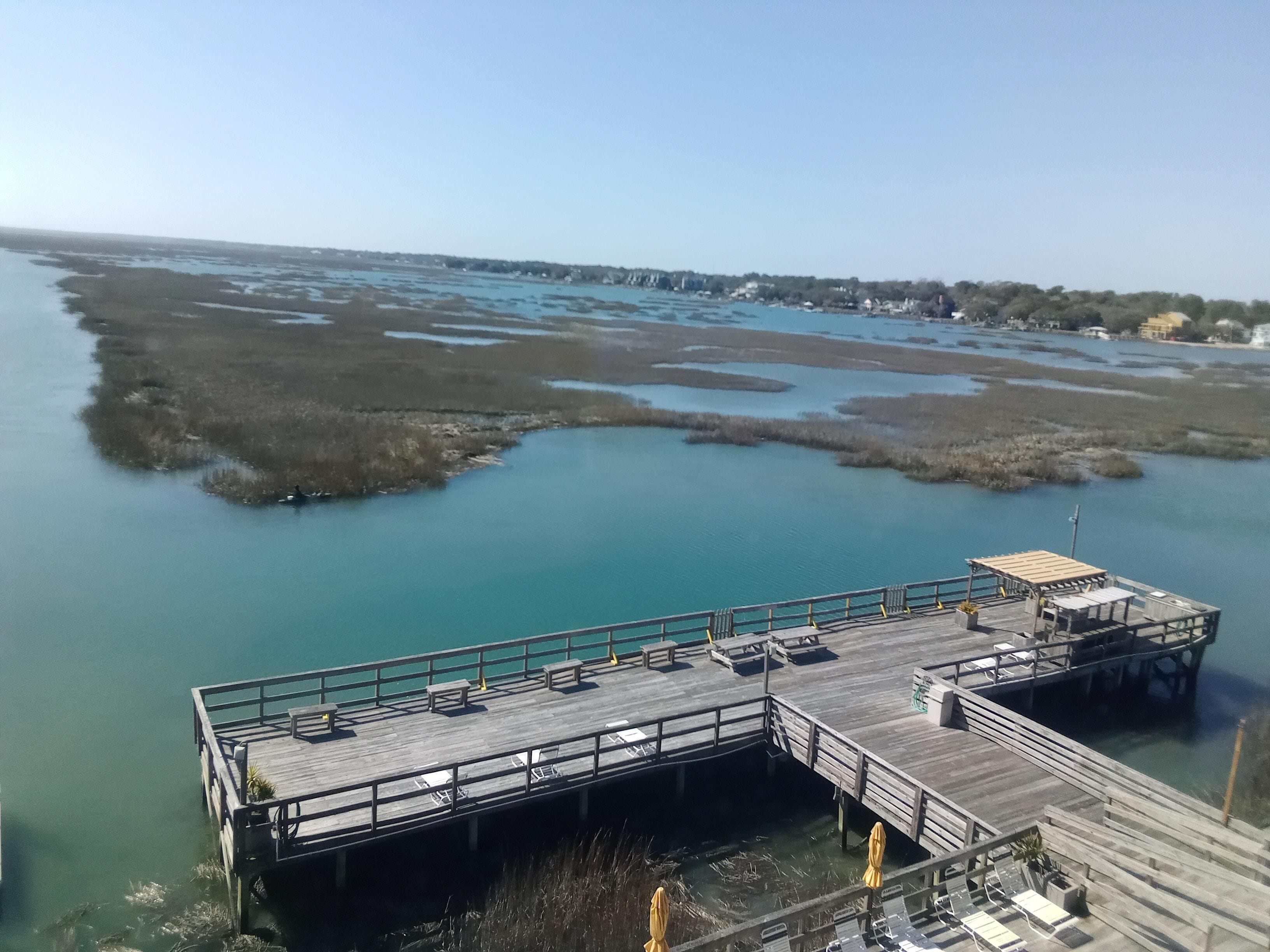 Un muelle de madera que se adentra en un cuerpo de agua, bajo cielos despejados.