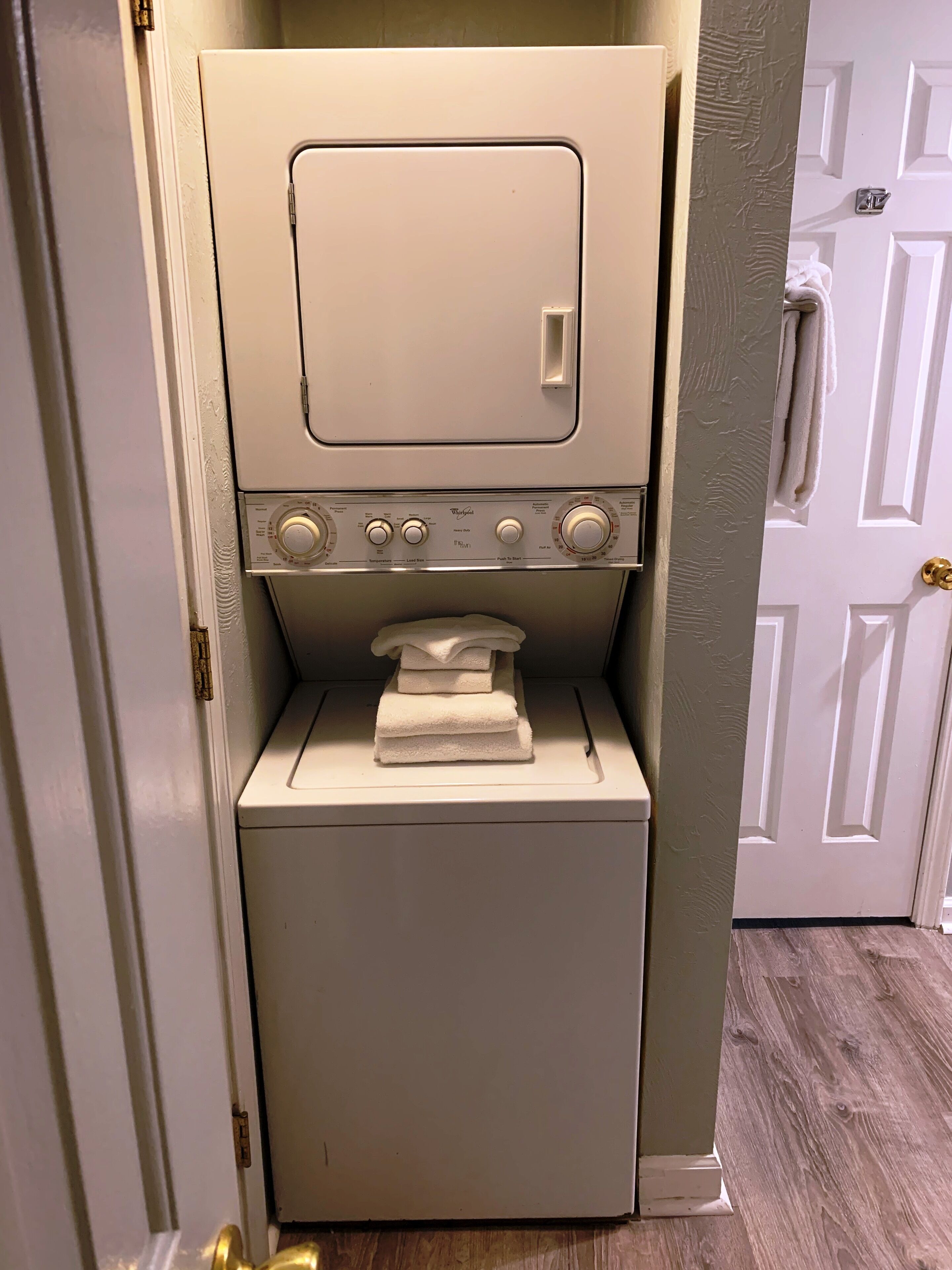 Une petite buanderie blanche, équipée d’un lave-linge et d’un sèche-linge superposés.