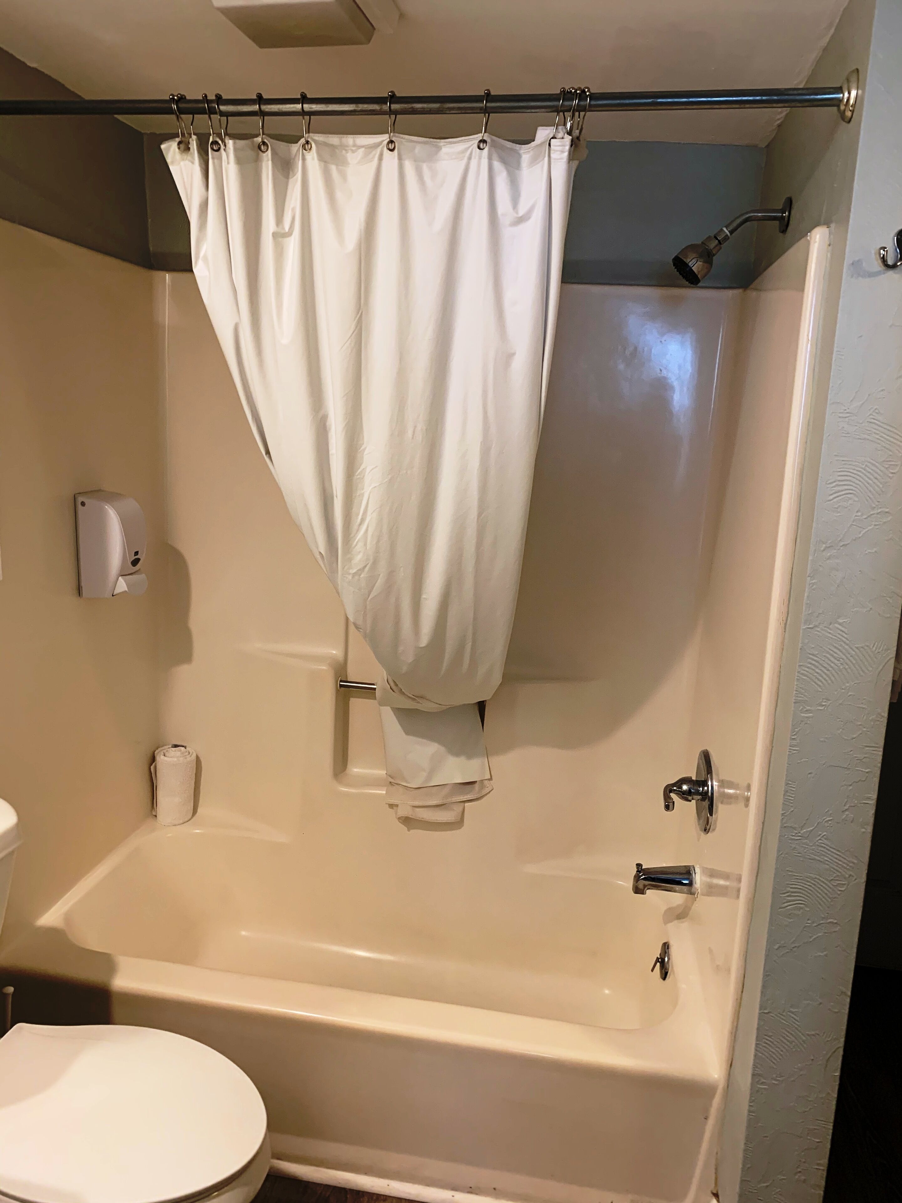 A bathroom with a bathtub, toilet, and shower curtain.