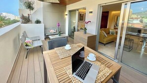 A modern balcony with a wooden table, a laptop, and a sofa. - Home2Book El Encanto 3 de Mayo (Santa Cruz de Tenerife)