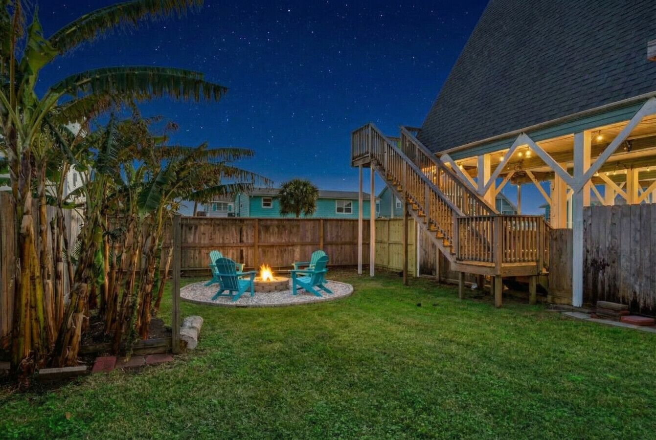 A backyard with a fire pit, two chairs, and a wooden deck.